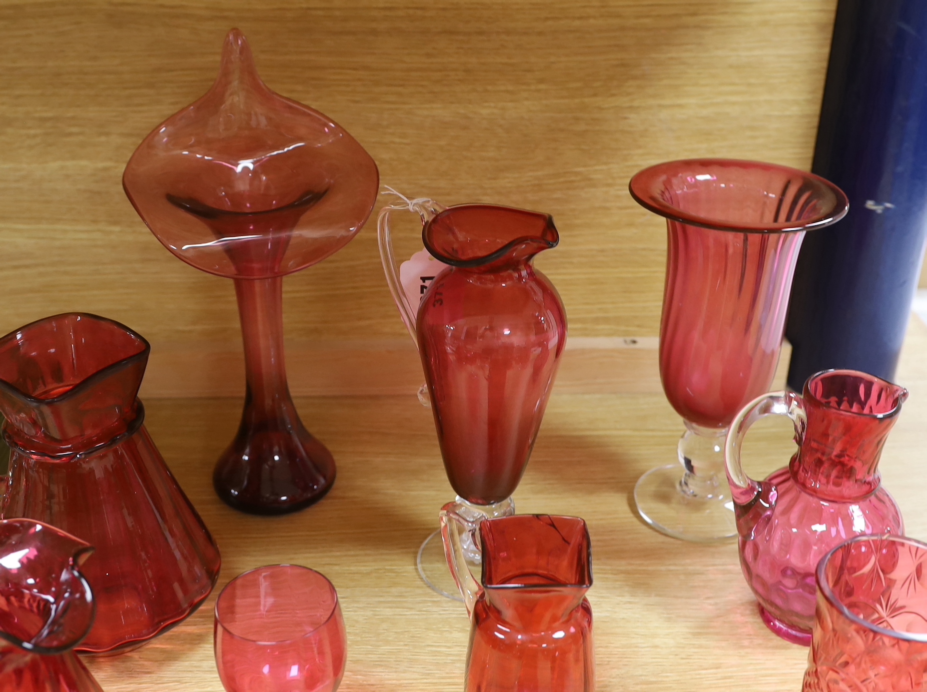 Cranberry glassware including vases, jugs, bowls and custard cups, the largest 33cm high